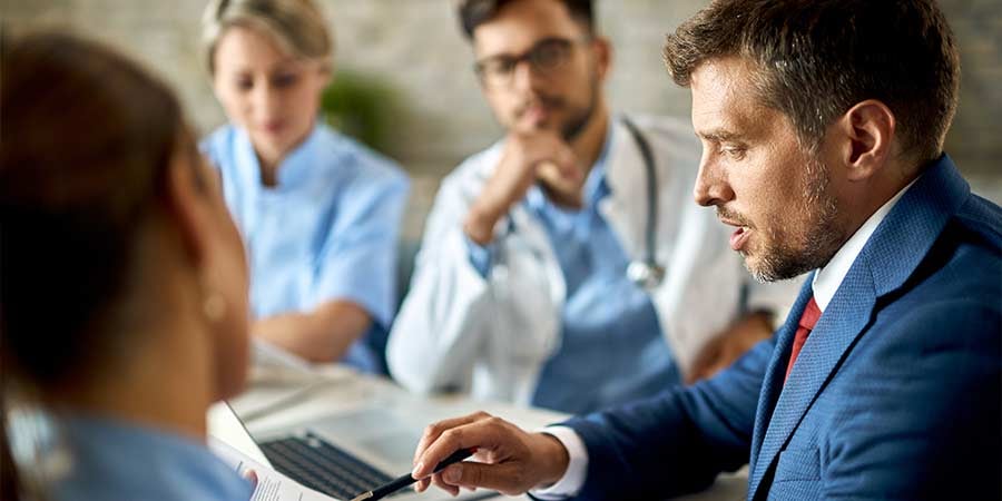 Healthcare professionals and facility leader reviewing compliance documents during a meeting on infection control and regulatory processes