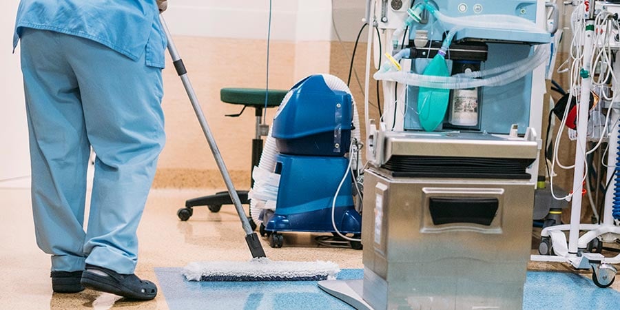 Hospital cleaning staff maintaining infection control standards near medical equipment