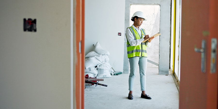 Healthcare construction professional inspecting a renovation area before temporary wall system containment setup in an active facility environment.
