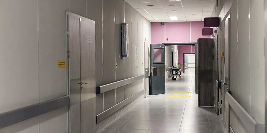 Hospital corridor with containment walls and controlled access doors in an active healthcare facility environment