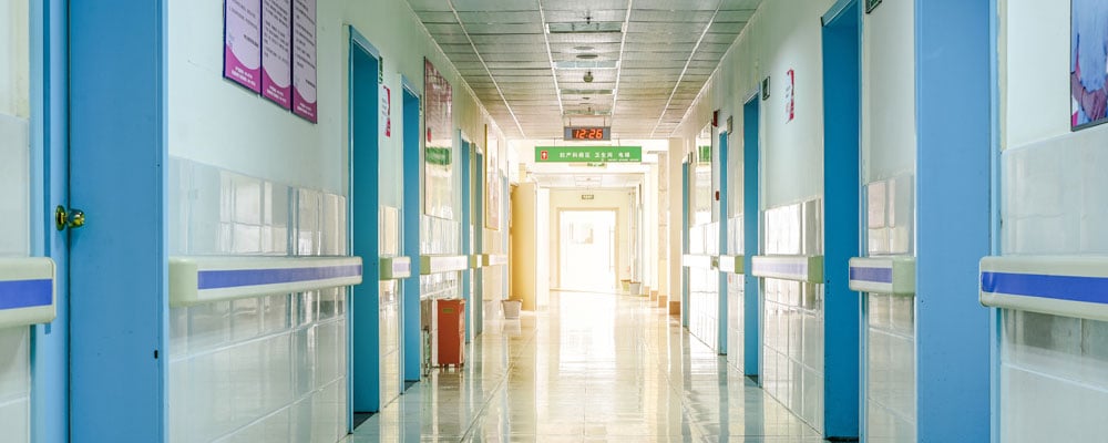 A hospital corridor, illustrating a section titled "Compliance Issues for Facilities Managers in Infection Control"