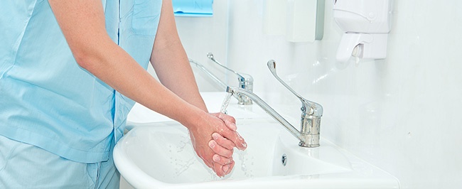 A healthcare professional washing their hands as part of a set infection control protocol in a healthcare setting.