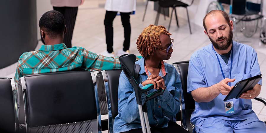 Healthcare staff member reviewing information with a patient in an ambulatory surgery center waiting area, highlighting clinical communication and patient care environment