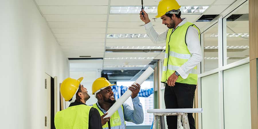 Construction workers installing ceiling panels in a hallway during an indoor renovation project