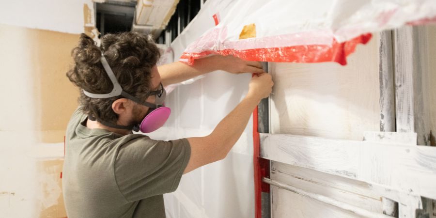 Man working on wall with respirator 