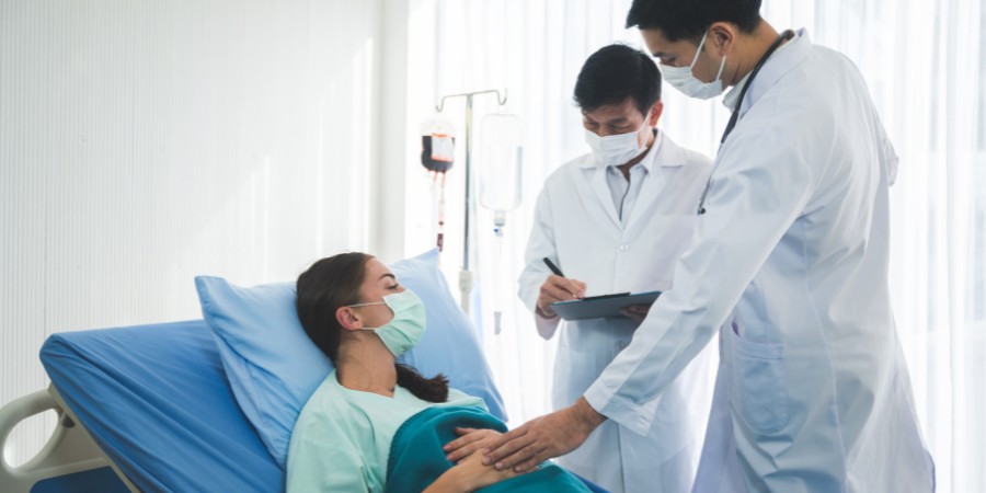 woman in hospital bed with doctors next to her