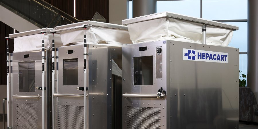 Row of HEPACART® containment carts with extendable ceiling barriers, viewing windows, and HEPA filtration units set up in a hospital corridor