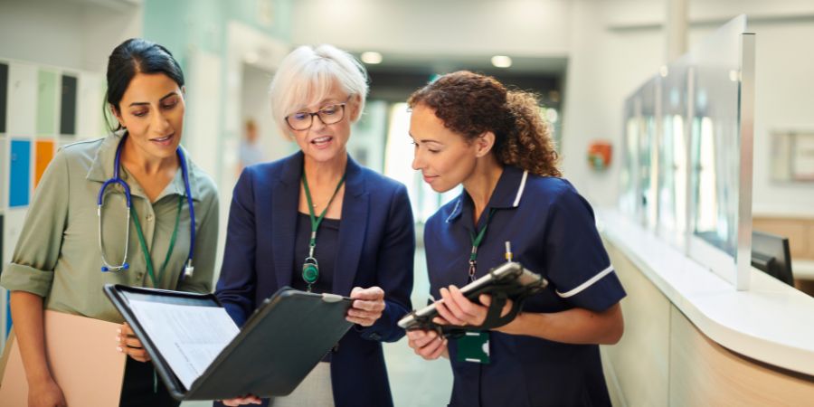 3 women looking at sheets from facility manager